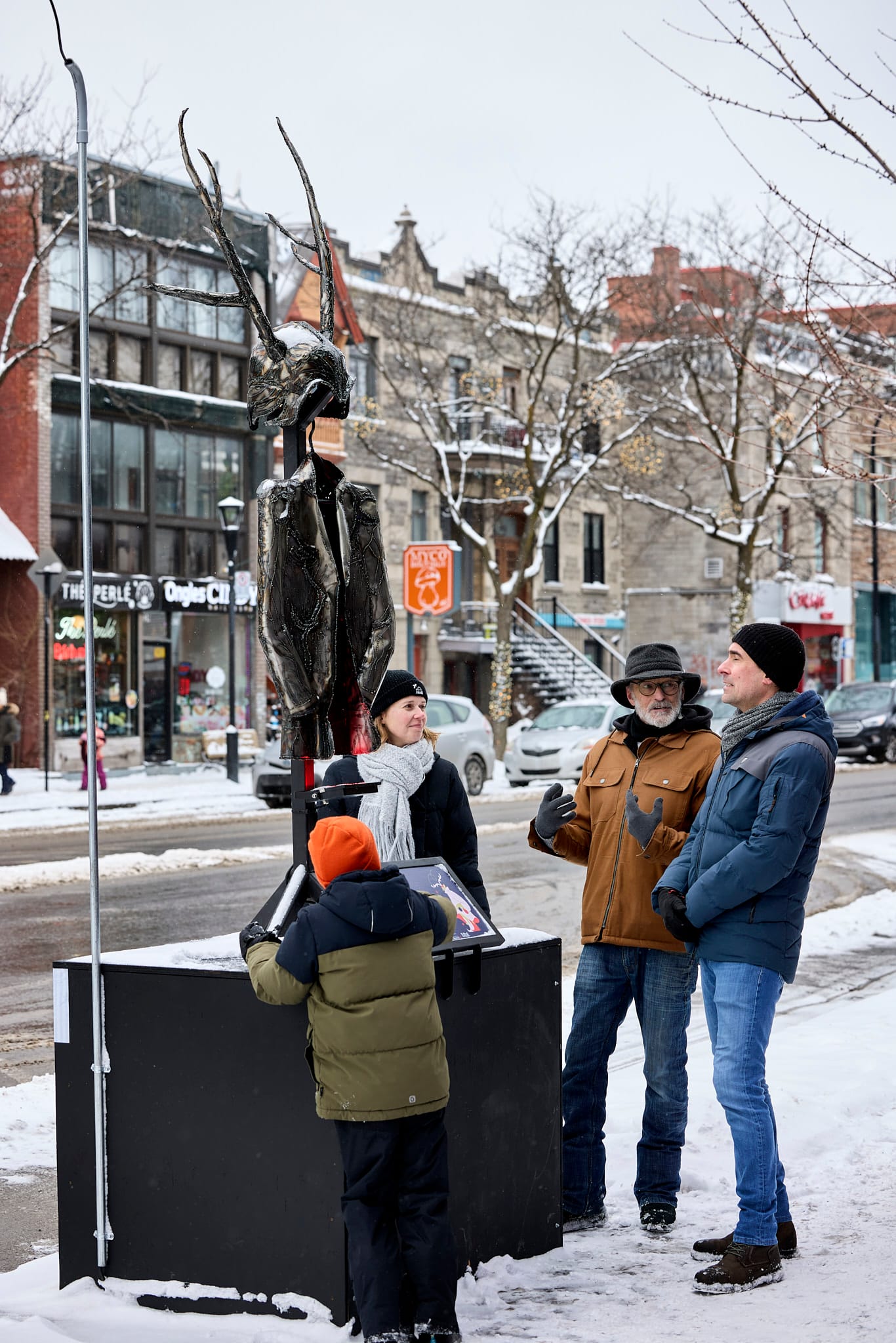 Quatre personnes observent une sculpture lumineuse métallique sur la rue Saint-Denis lors de la première édition du Festival Conte(mporain).