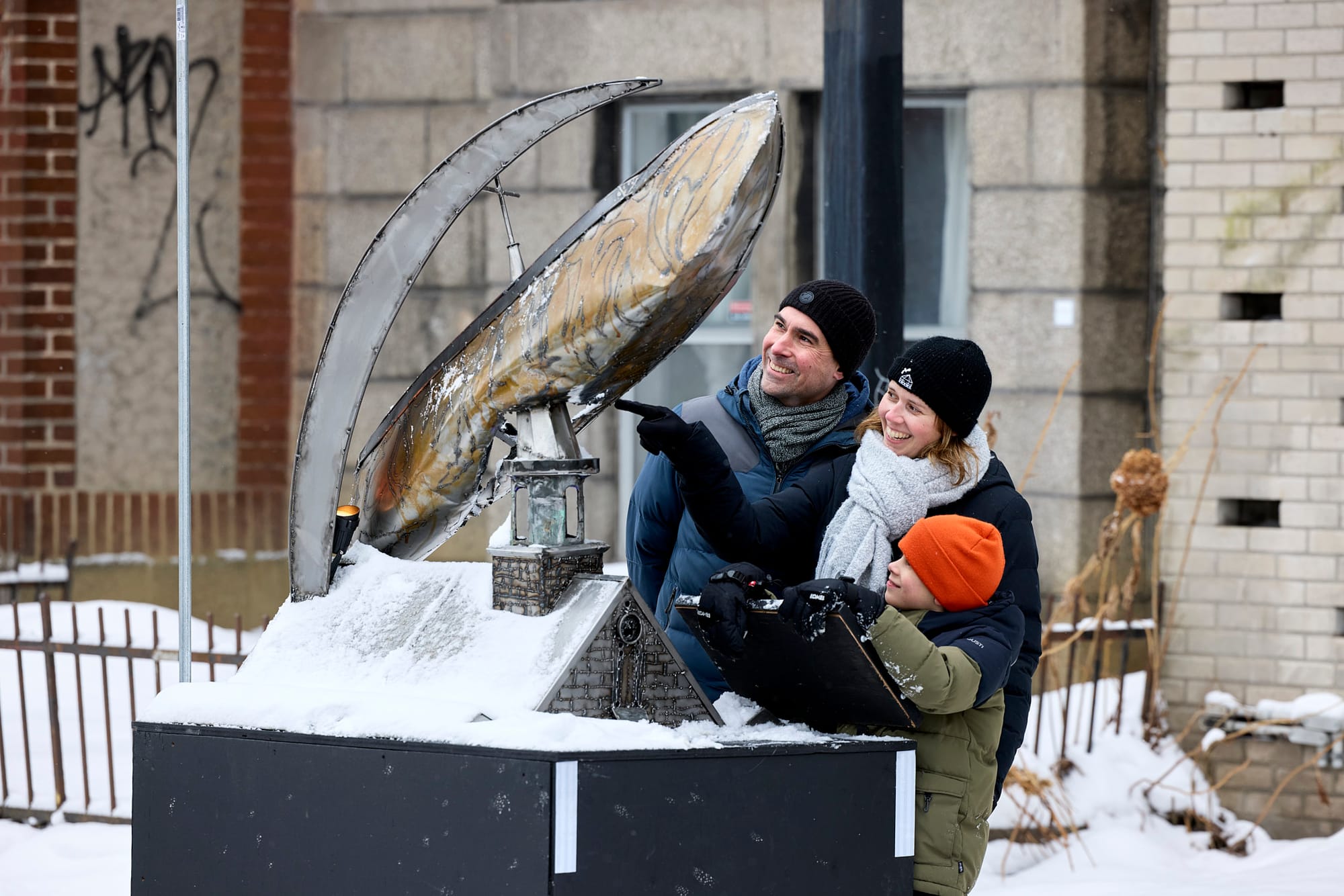 Une famille observe une sculpture inspirée du conte de la Chasse-galerie.