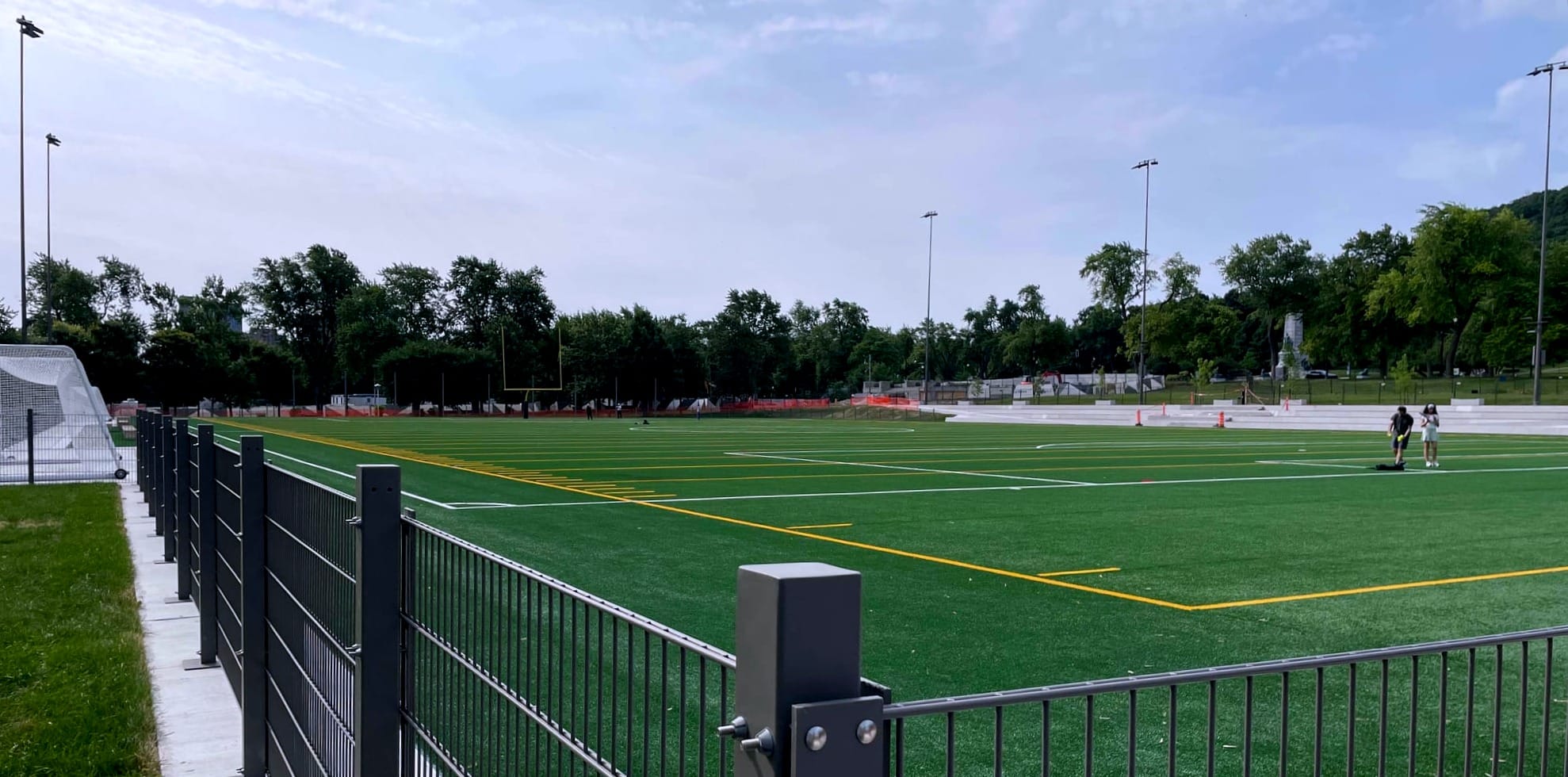 La photo montre la surface verte avec des lignes jaunes et blanches pour la pratique de différents sports.