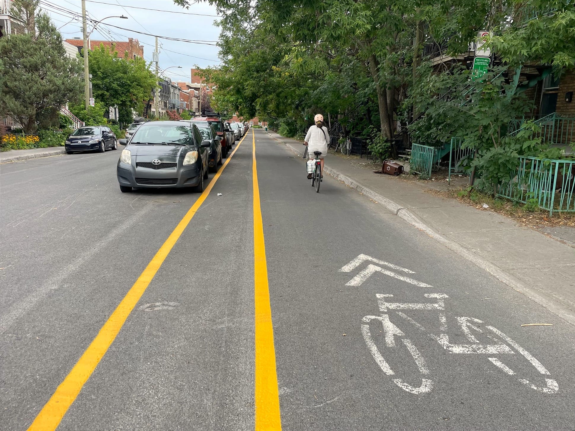 Une cycliste emprunte la voie cyclable sur Casgrain vers le sud, alors qu'à sa gauche, des voitures sont garées de manière à faire face au nord.