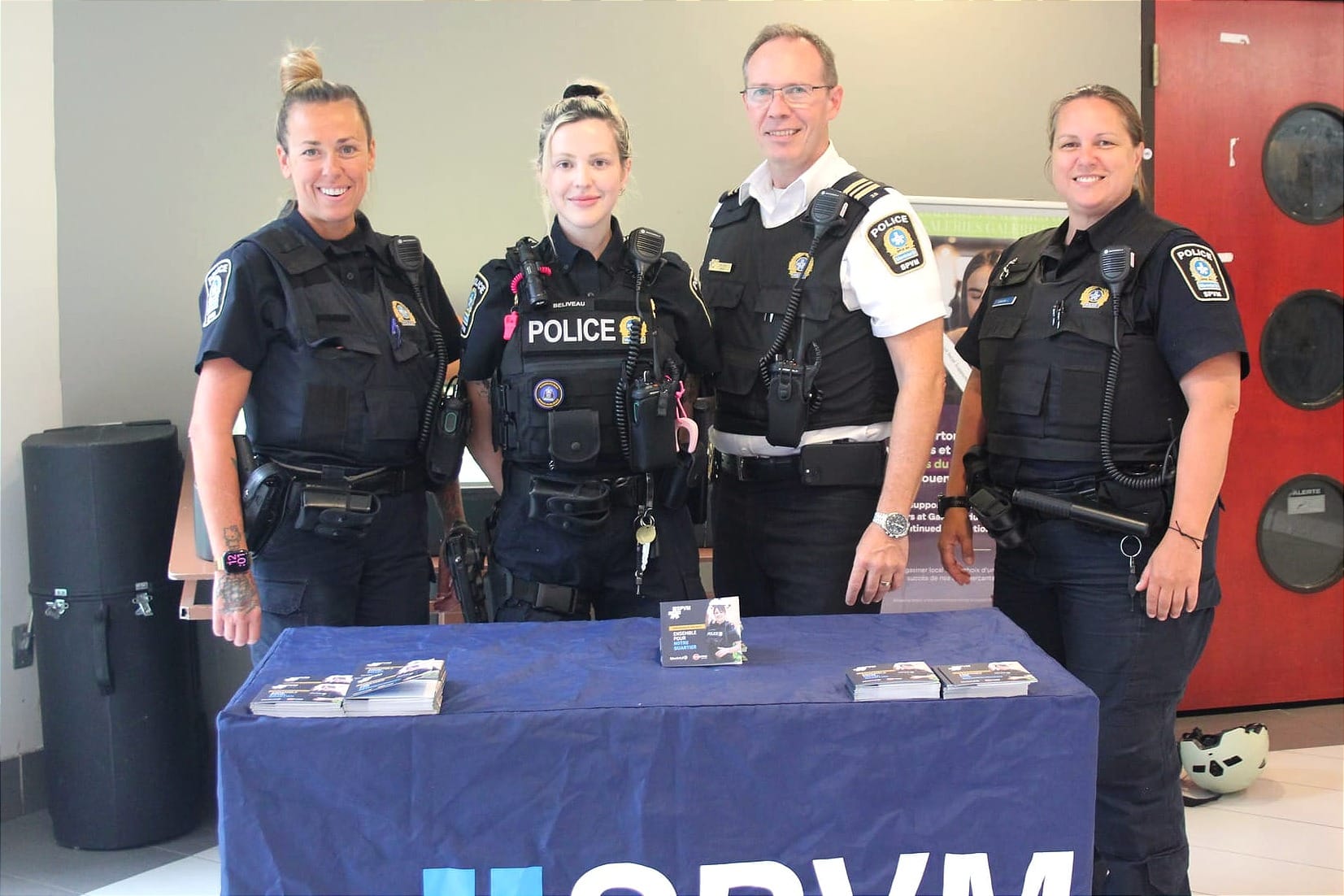 Les quatre policiers posent debout, derrière la table portable du SPVM.