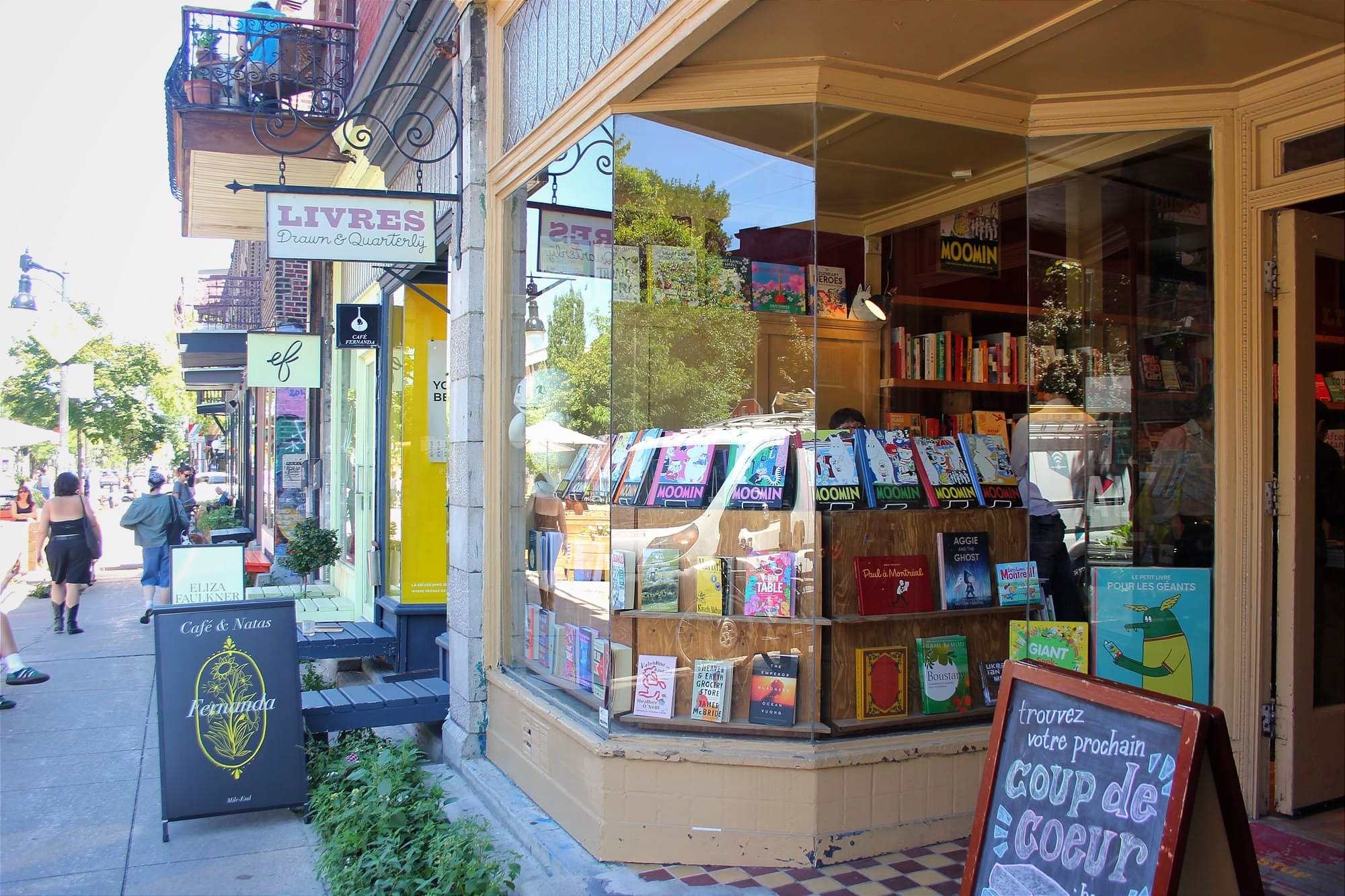 Vue sur l'enseigne et la vitrine de la librairie ainsi que le trottoir sud de la rue Bernard Ouest. 