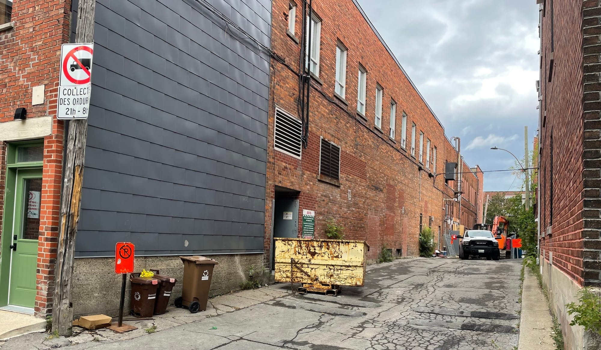 Cette photo de la ruelle montre des camions et des pancartes qui bloquent le passage.