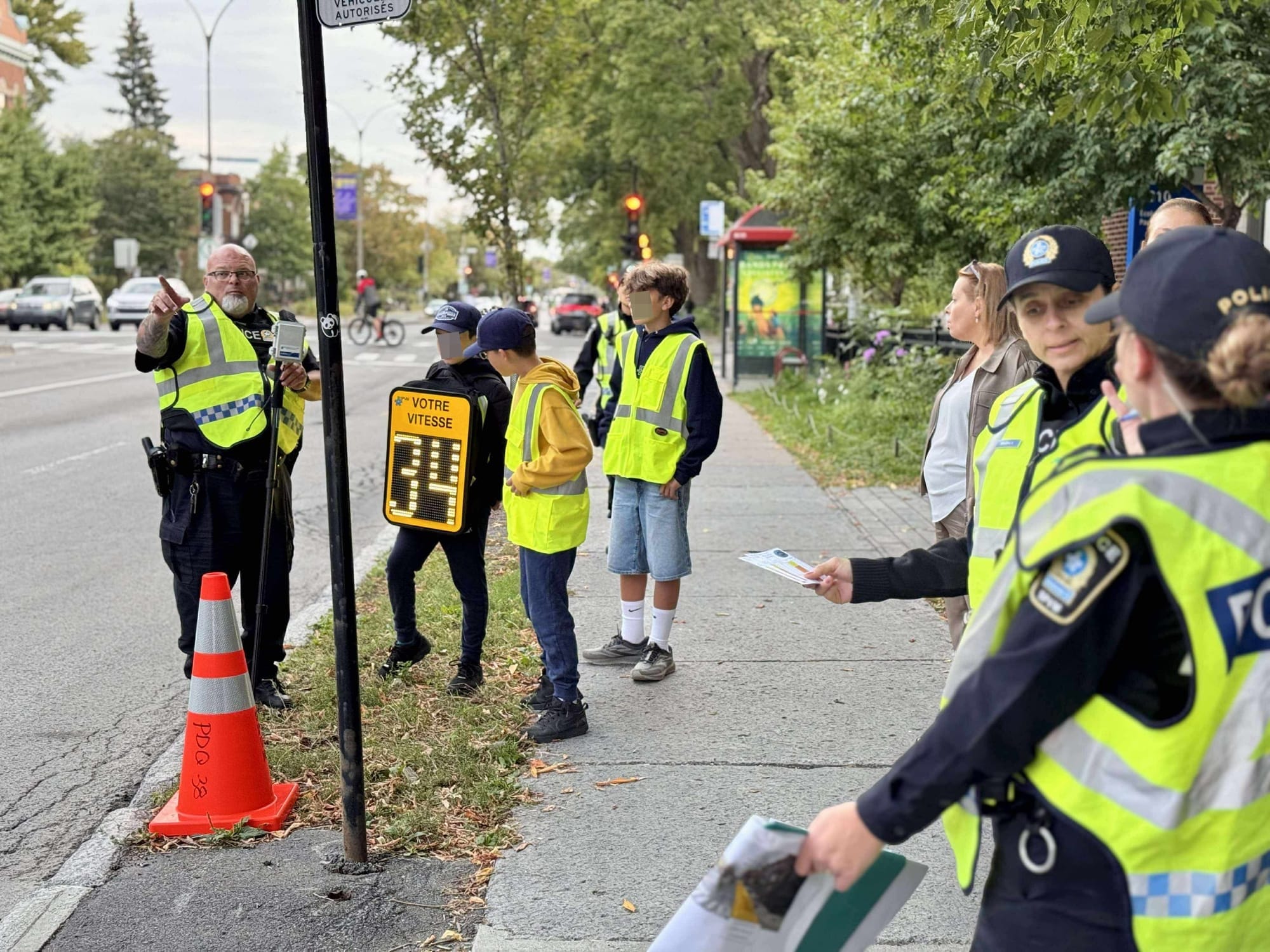 Quelques élèves, membres du personnel scolaire et policiers sont sur le trottoir du boulevard Saint-Joseph. 