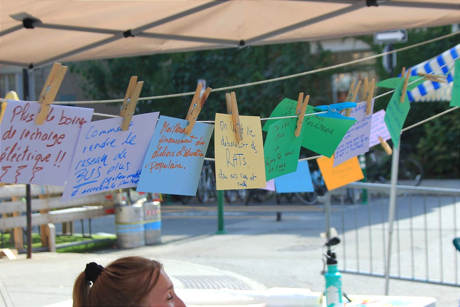 Des cartons avec des messages soulignant divers enjeux sont accrochés sur une corde qui fait le tour d'un kiosque. 