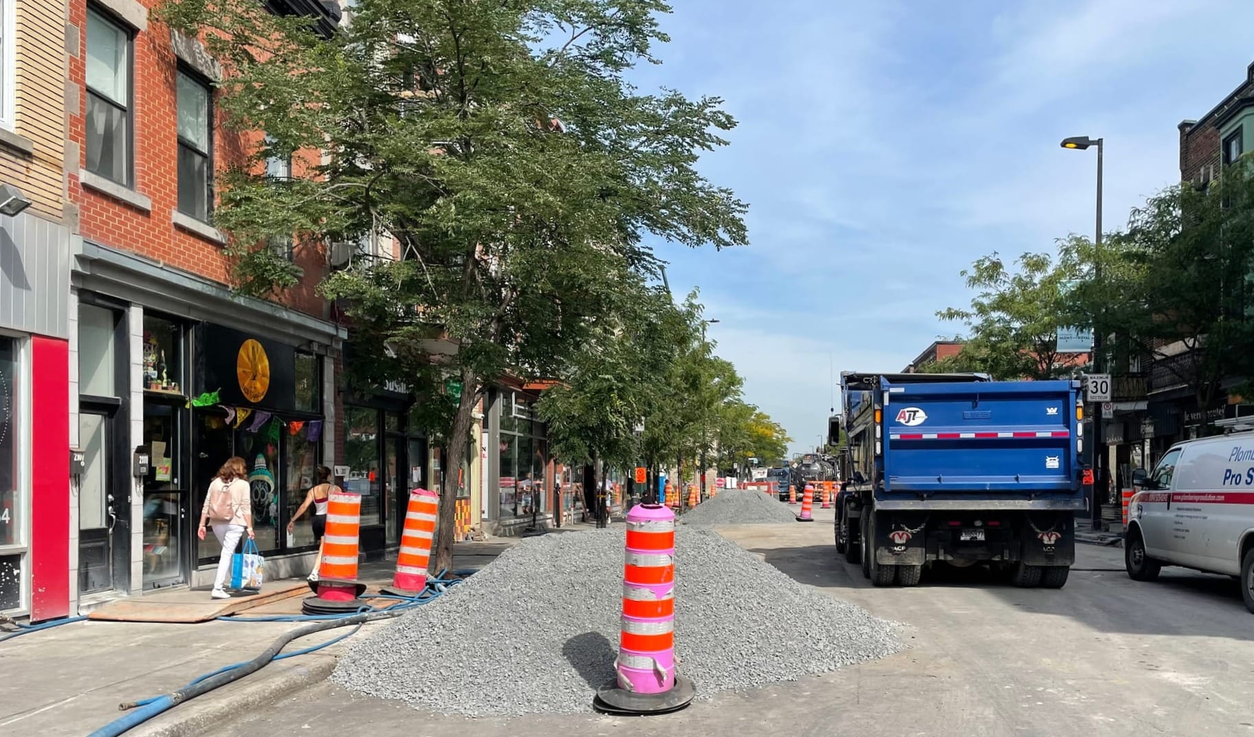 Cette photo montre l'avenue fermée où se trouvent des tas de graviers, des cônes et des camions.