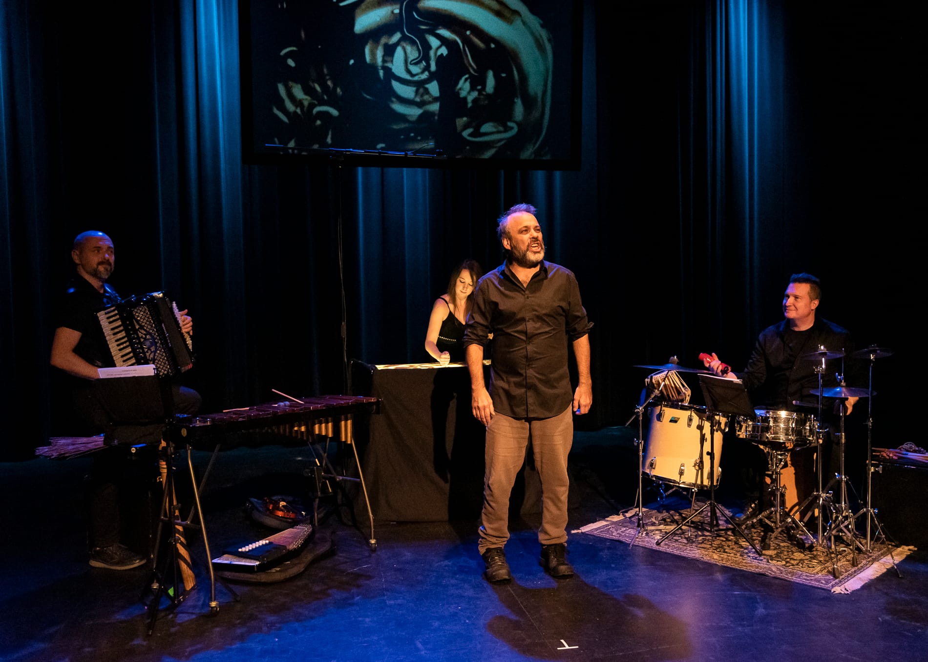Jocelyn Sioui en performance, devant ses deux musiciens et l'artiste de sable.
