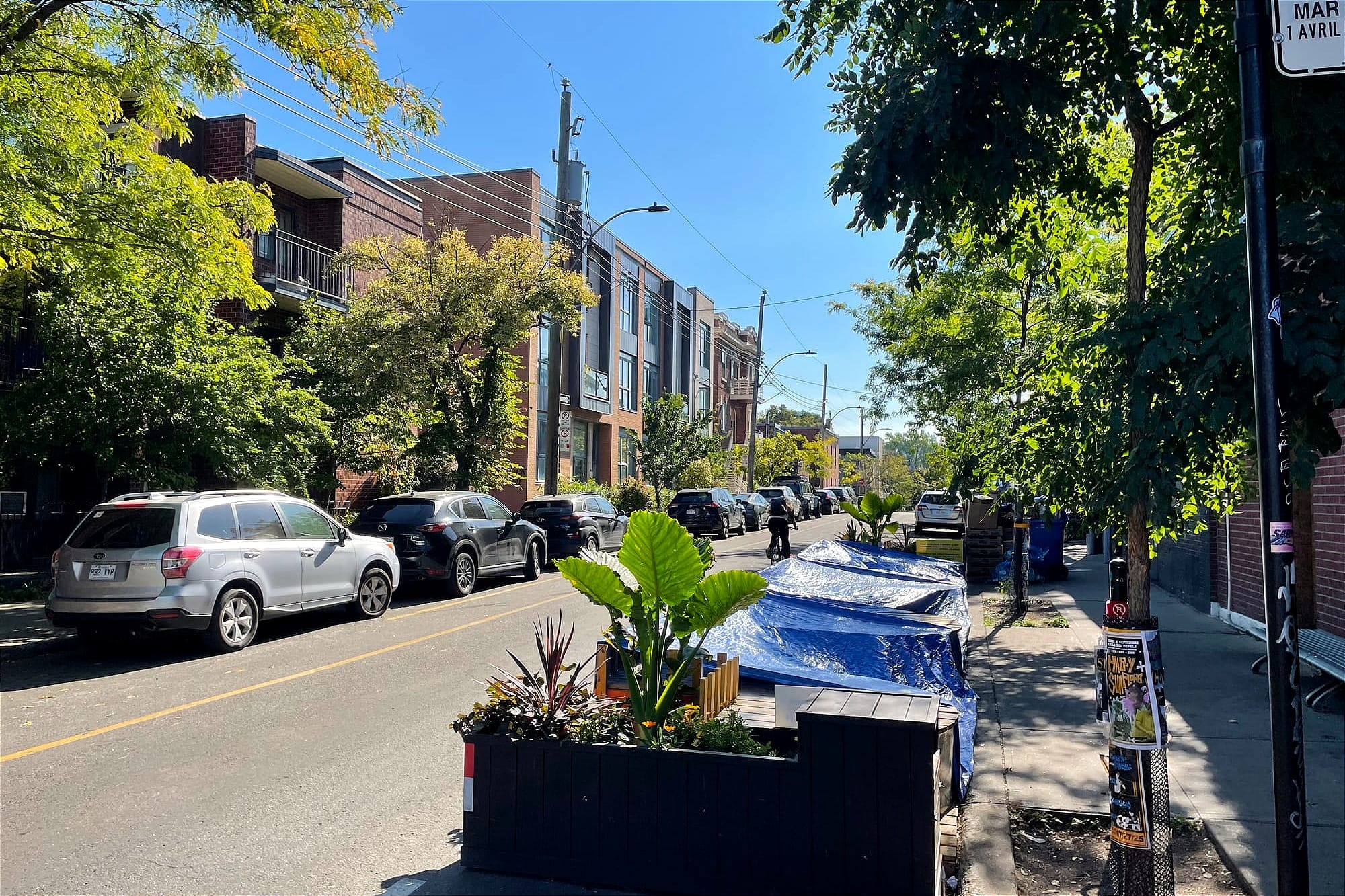 Pris de vue de la rue Clark où l'on voit le placottoir recouvert à droite, et un cycliste un peu plus loin sur la voie tranquille. 