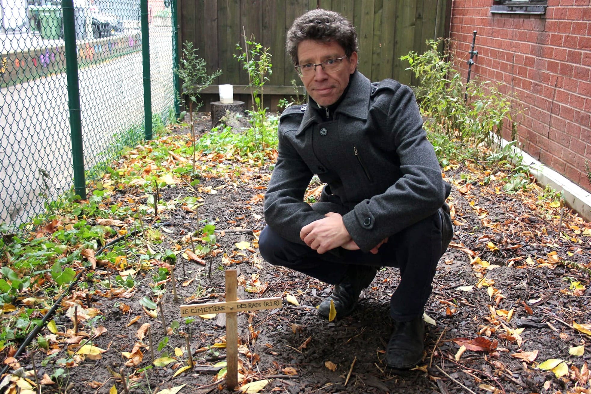 M. Fradette est accroupi à côté de petits bâtons qui marquent les lieux où sont enterrées les bêtes. Une croix plus imposante identifie le cimetière. 