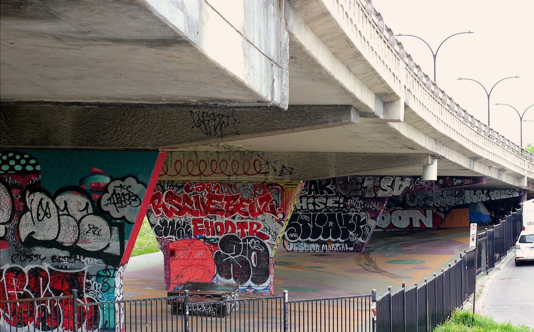 Le viaduc passe du haut du cadre à gauche vers la droite, avec ses structures de soutien graffitées. 