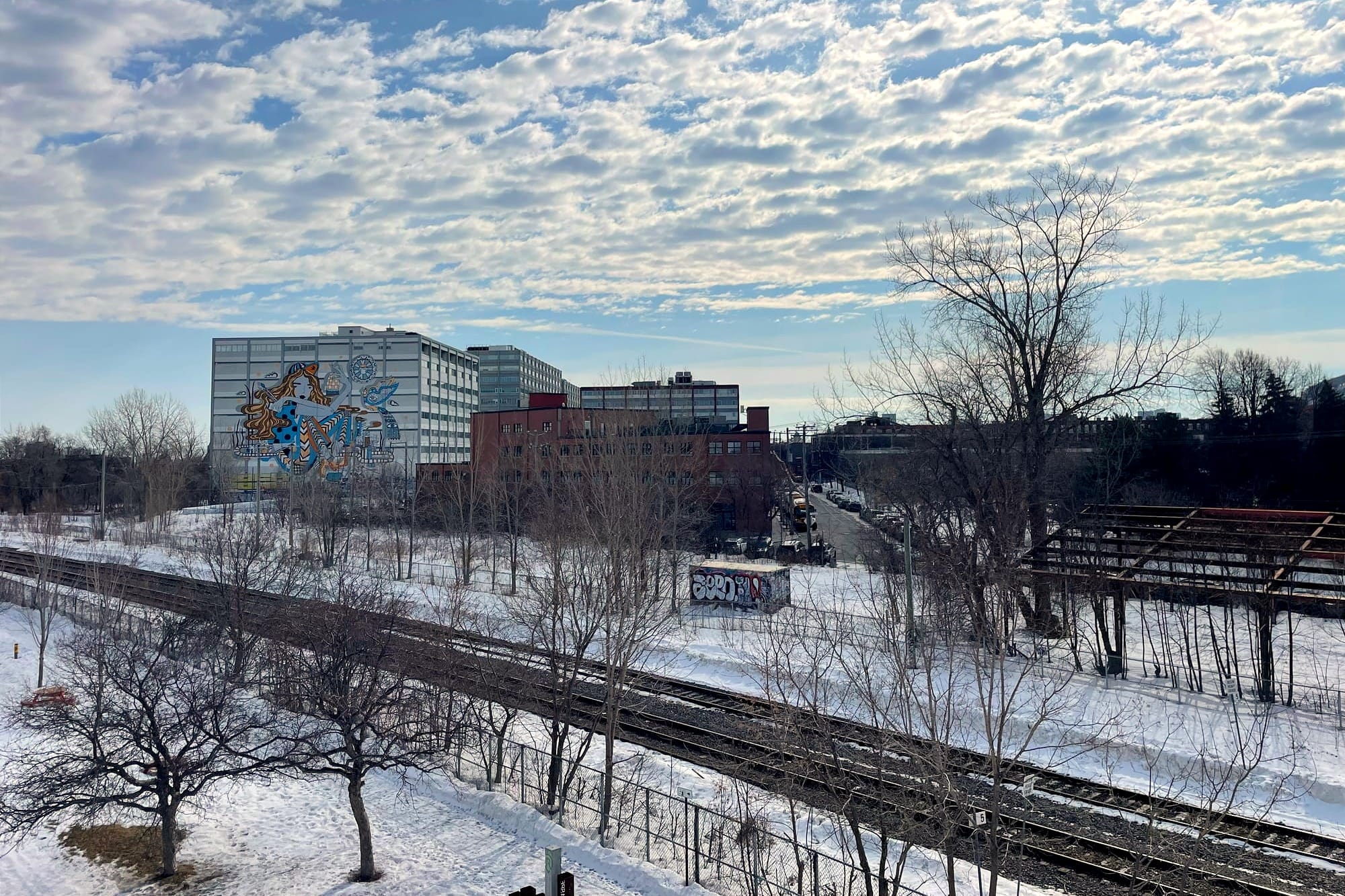 Vue du chemin de fer en hiver, à partir du viaduc sur le côté nord. On voit les édifices du Mile End en arrière-plan.
