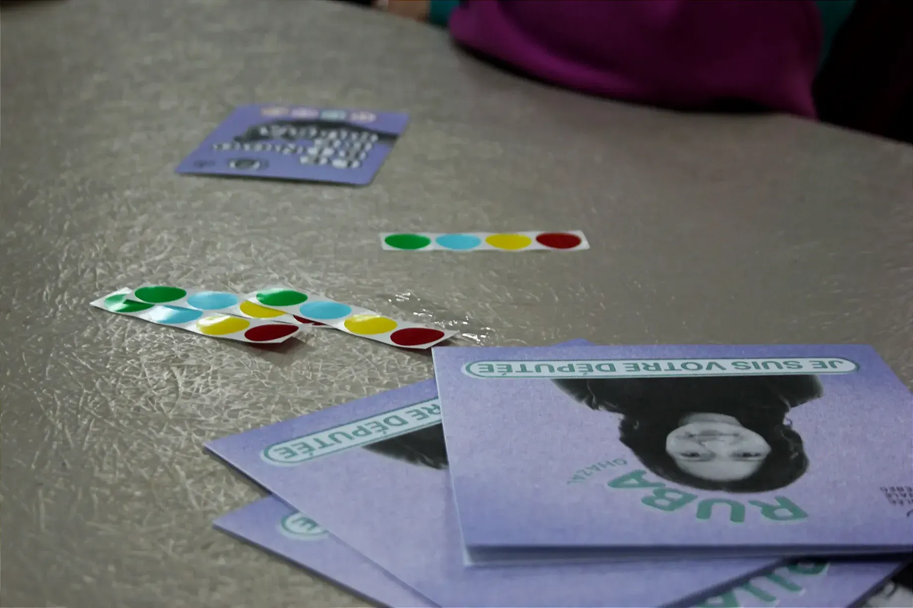 Des dépliants rassemblés en éventail côtoient des collants et une carte de bingo. 