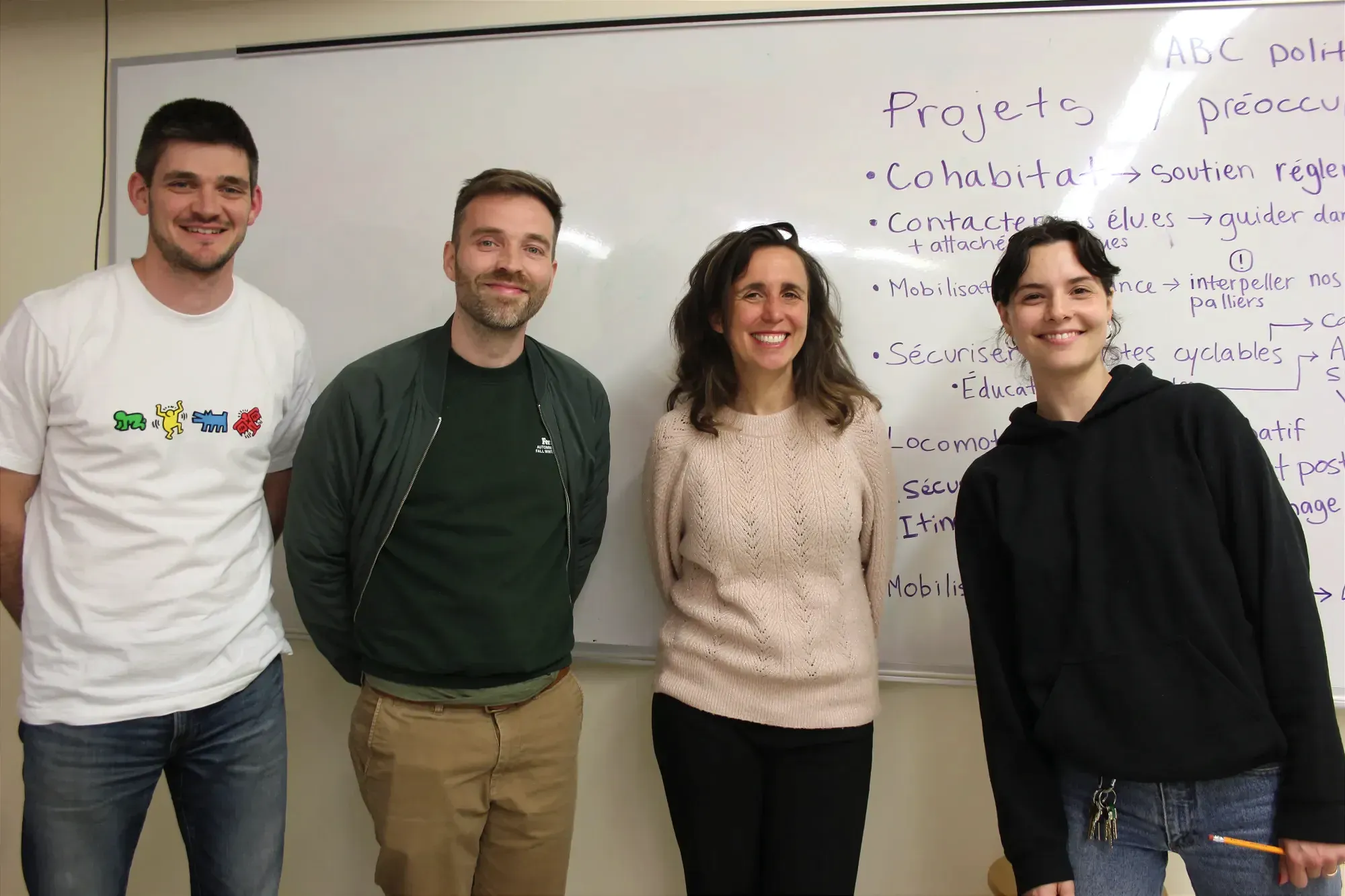 Mme Vilain pose devant un tableau blanc, entourée de participants de l'atelier. 