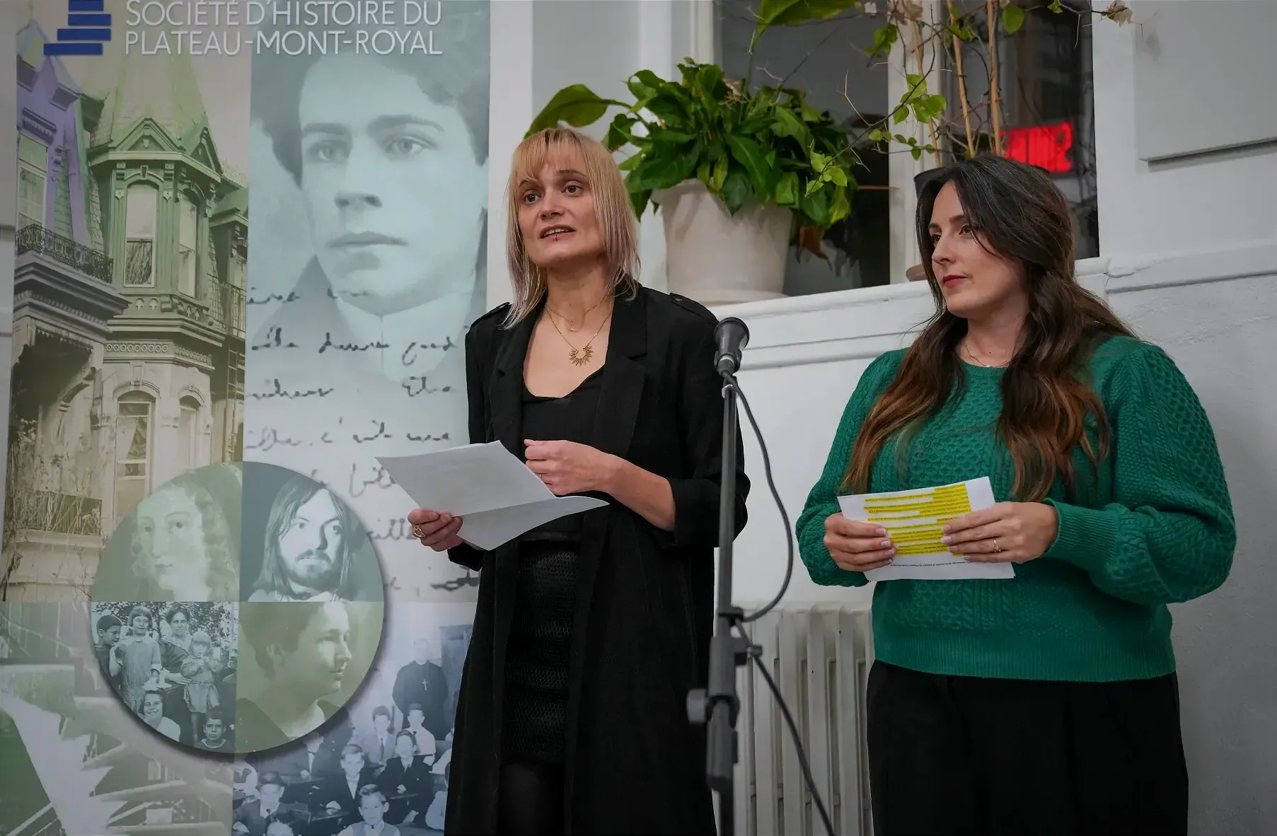 Les deux dames sont debout devant un microphone, et à la droite d'une bannière de la Société d'histoire du Plateau-Mont-Royal.