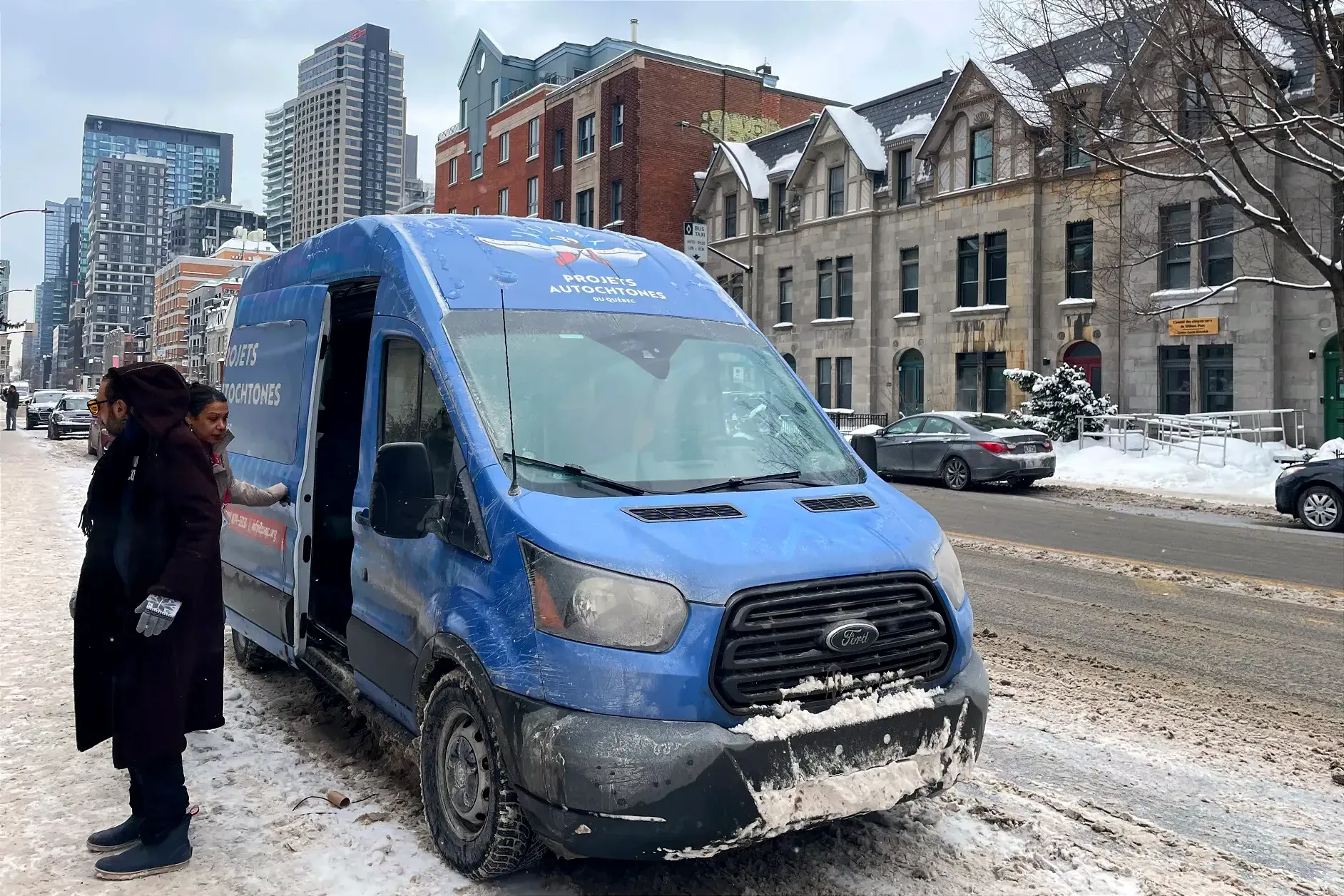 Une femme referme la porte glissière de la fourgonnette bleue sur lequel ont peut voir le logo de PAQ.
