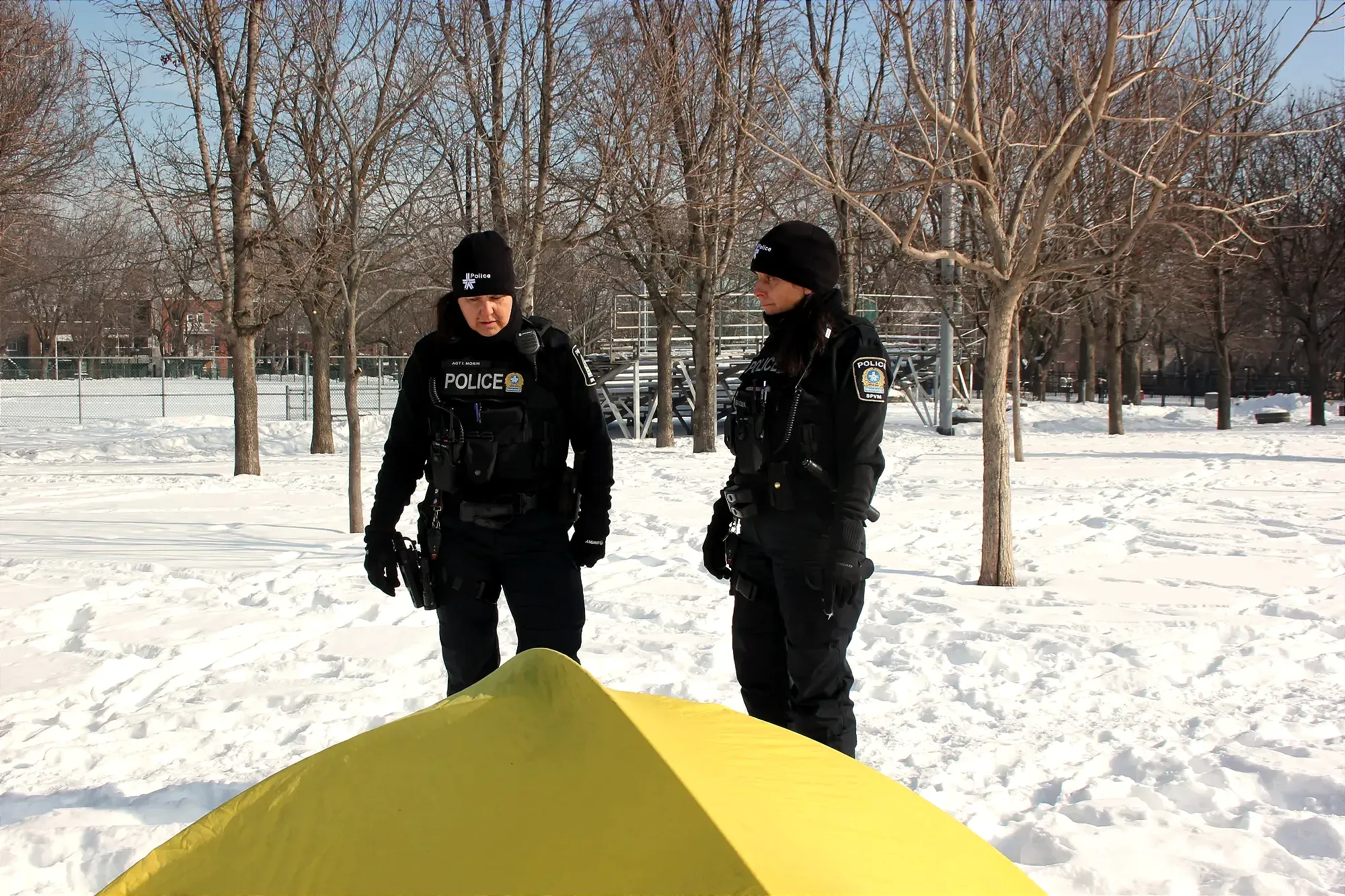 Isabelle Morin et Véronique Brazeau sont debout, faisant face à la tente jaune dont le sommet apparaît au bas du cadre.