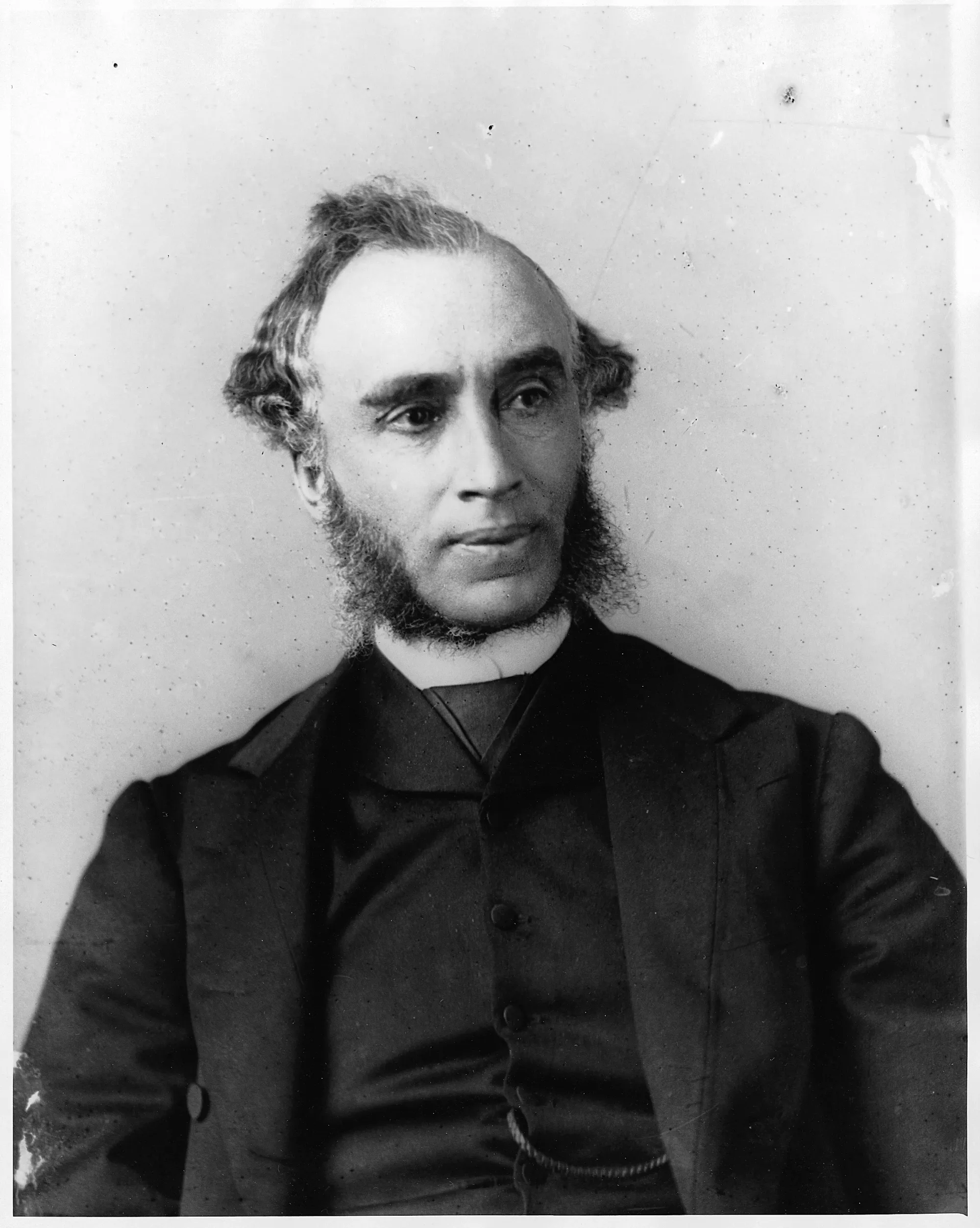 M. Wright pose pour la caméra, vêtu d'un complet, en regardant vers la droite du cadre. 