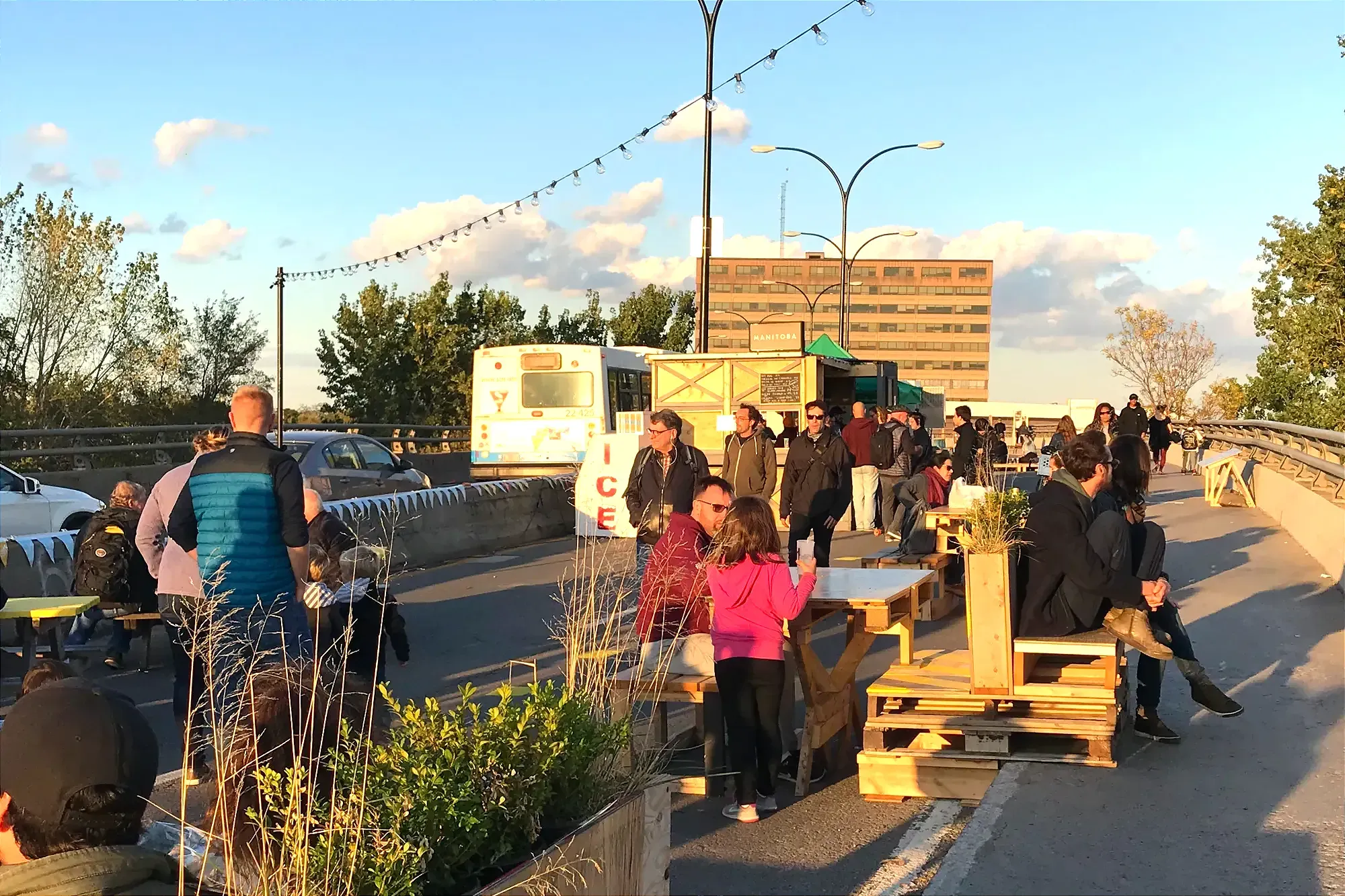 Plusieurs personnes profitent d'une aire de plaisance sur le viaduc. Un commerce peut être aperçu à l'arrière-plan.