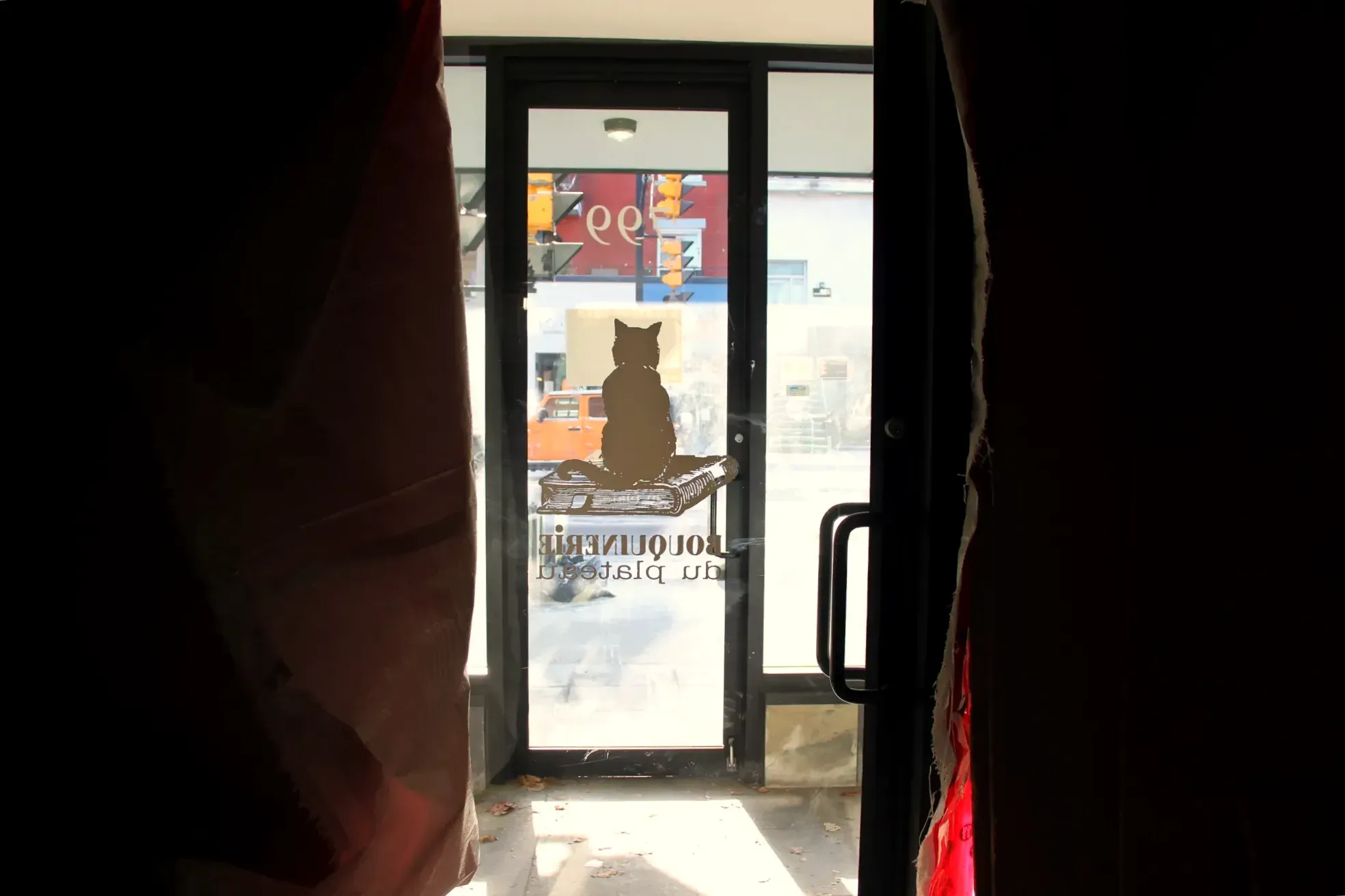 Vue de la porte d'entrée de La Bouquinerie, sur laquelle est illustré un chat qui semble patienter en attendant la réouverture.