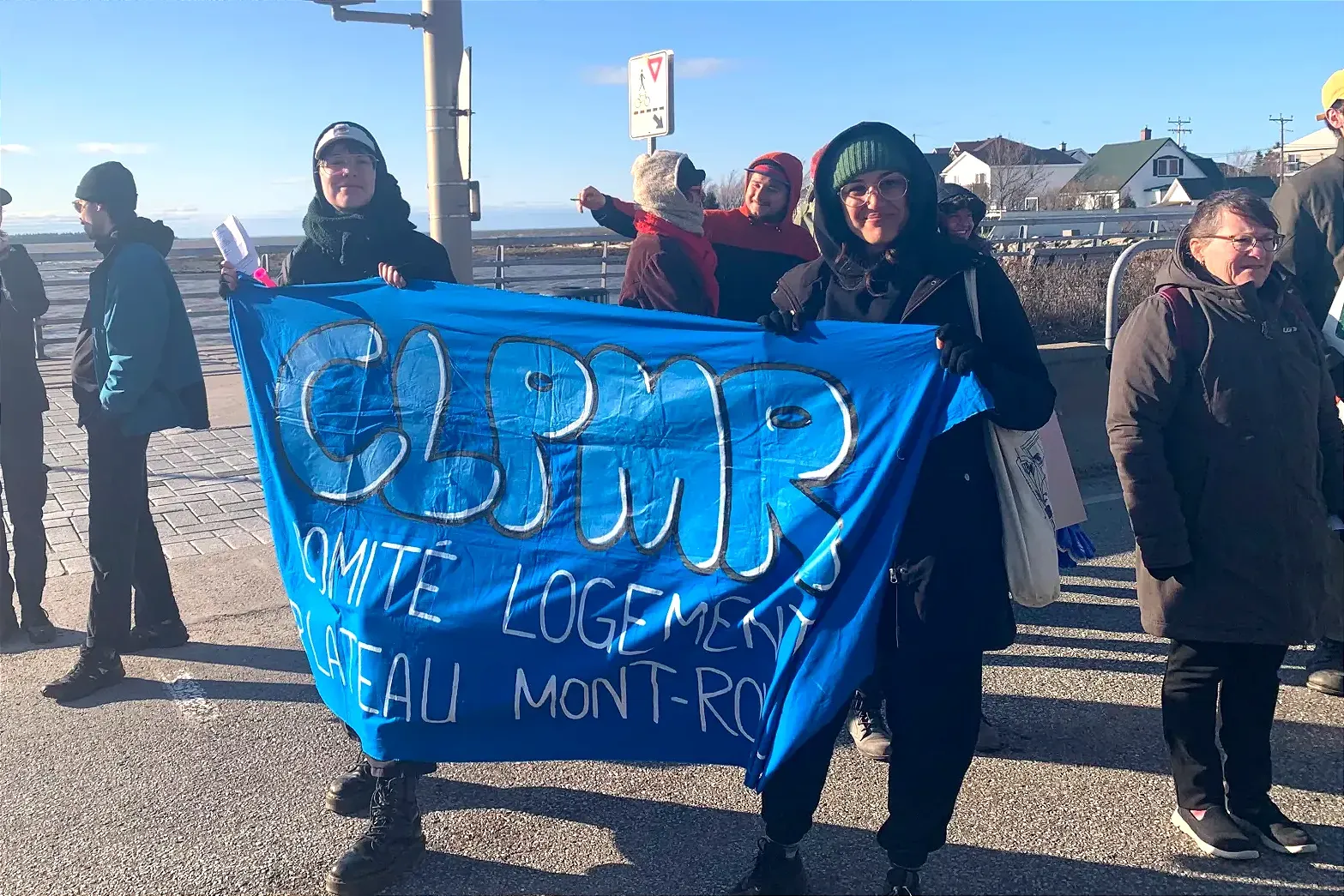 Les deux femmes semblent être en contexte de manifestation, dans un contexte régional, près de l'eau.