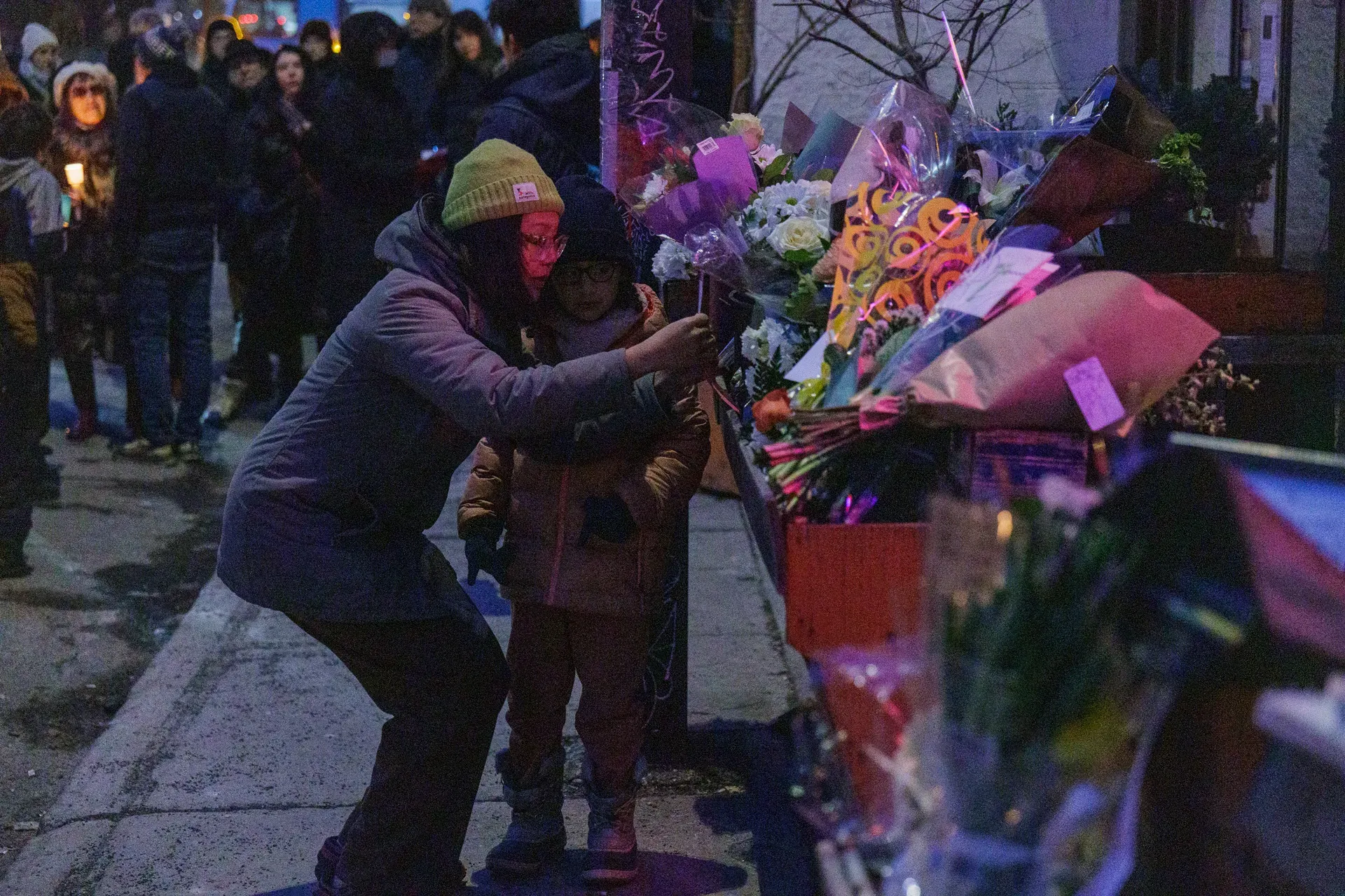 Une femme est accroupie à côté d'une enfant et près de l'étalage de bouquets.