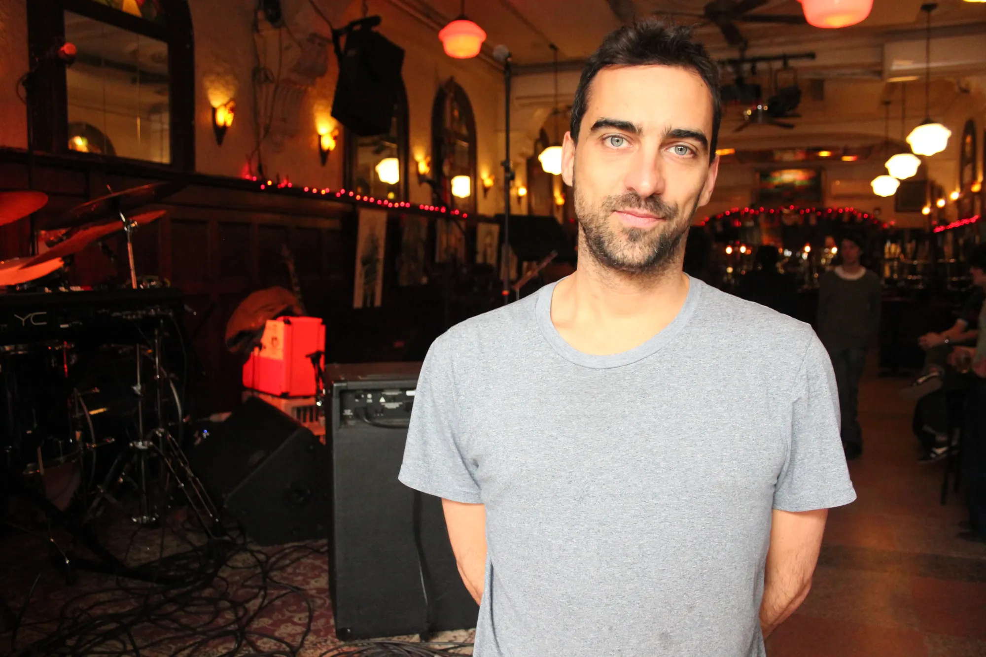 M. Gauliard-Martineau pose à l'intérieur du Quai des brumes. On peut voir l'éclairage rougeâtre derrière lui et un bout de la scène, à sa droite.