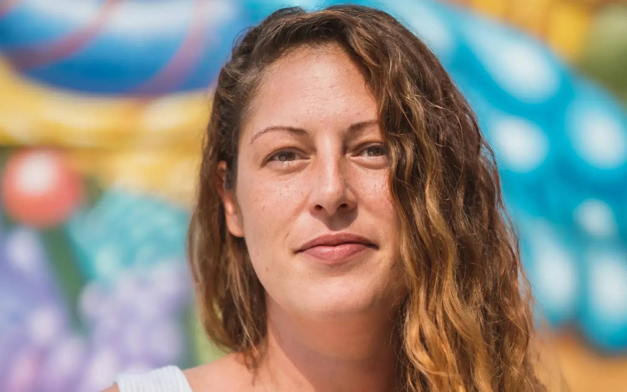 Portrait extérieur de Mme Morizio, sur fond de murale colorée.