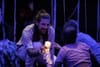 Un homme tend une méduse lumineuse vers des spectateurs dans le contexte du pièce de théâtre immersive.