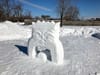 Un visage avec la bouche ouverte et la langue sortie, sculpté dans la neige.