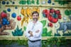 M. Guilbeault pose devant des conteneurs sur lesquels sont peintes des images de légumes et d'animaux.