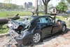 Une voiture a été écrasée par un arbre. On voit la carrosserie endommagée et les vitres cassées.
