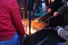 Un feu de joie autour duquel l'on voit plusieurs mains avec des baguettes en bois et des guimauves.