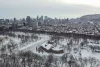 Le chalet et l'étang du parc La Fontaine sous la neige et le centre-ville et le Mont-Royal en arrière plan.