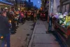 À droite : la façade du dépanneur, ornée de bouquets de fleurs. À gauche, la foule en demi-cercle, chandelles à la main.