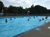 Une vingtaine de personnes sont dans l'eau turquoise de la piscine, avec l'eau jusqu'au torse.