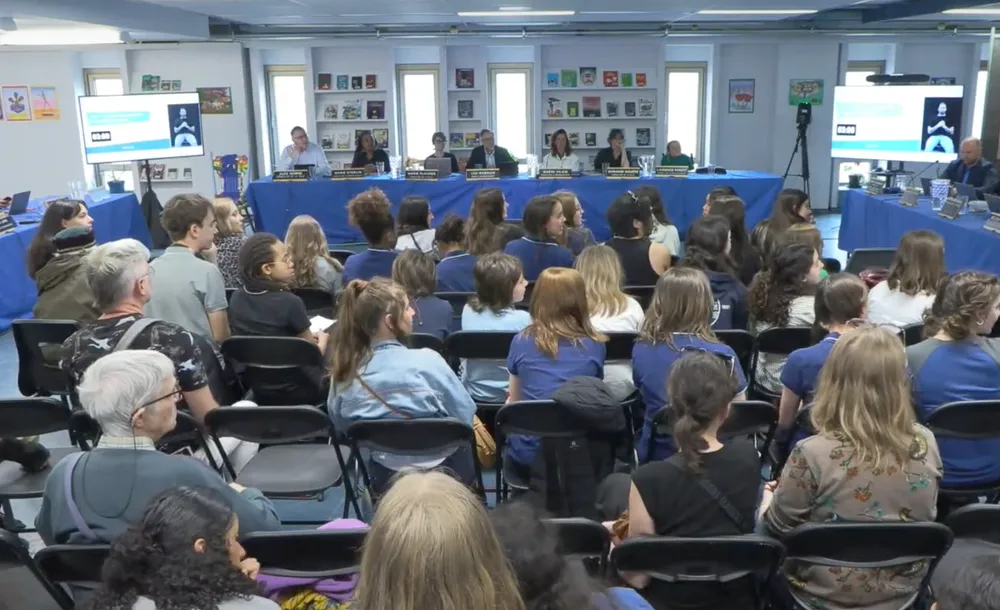 Cette photo tirée de la captation en direct de la séance montre à l'avant-plan de nombreux jeunes assis sur des chaises.