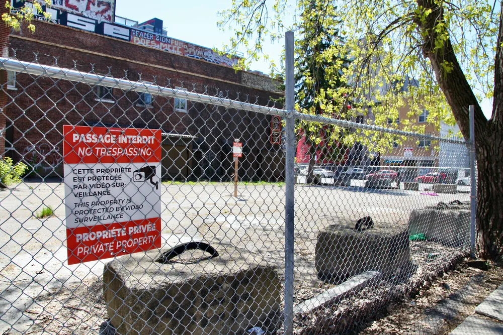 Un site vide entouré d'une barrière avec une affiche "Passage interdit".