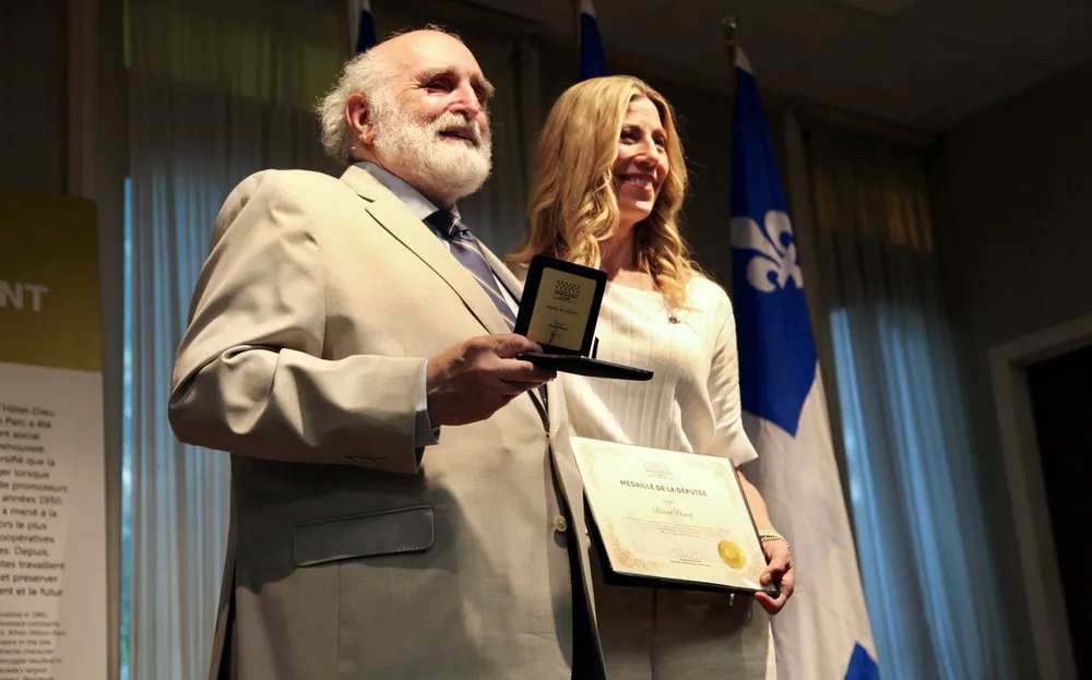 Richard Phaneuf tient le coffret avec la médaille et Jennifer Maccarone tient un certificat.