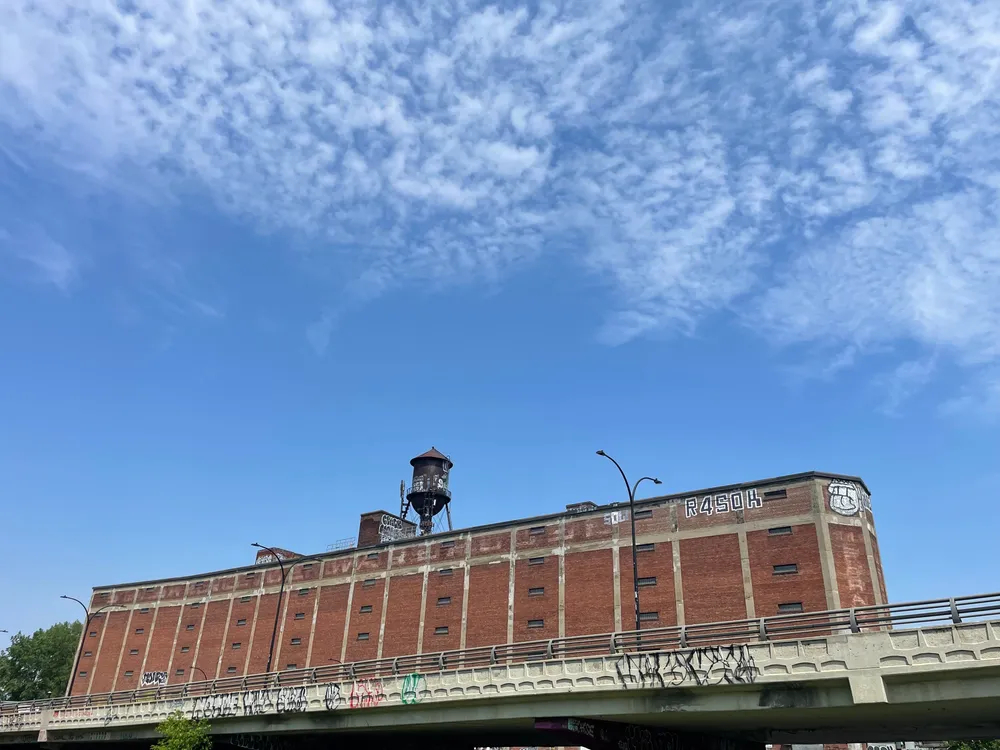 L'entrepôt en brique avec son château d'eau et un ciel bleu.